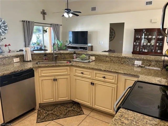 Kitchen featuring electric stove, stainless steel dishwasher, sink, and cream cabinetry