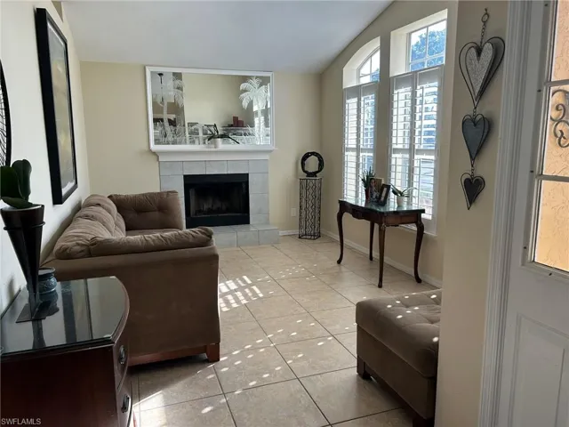 Tiled living room featuring a tile fireplace and lofted ceiling