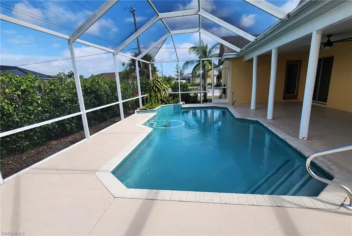 View of pool with a patio area, ceiling fan, and glass enclosure