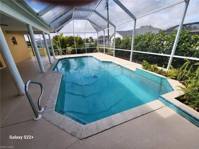 View of pool with a patio and glass enclosure