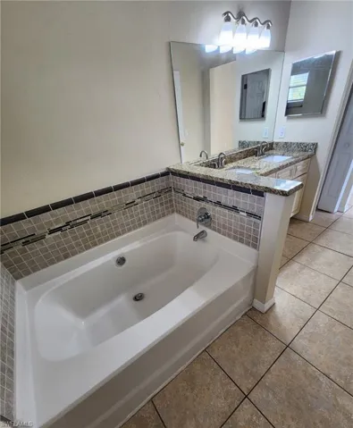 Bathroom with vanity, tile patterned flooring, and a tub