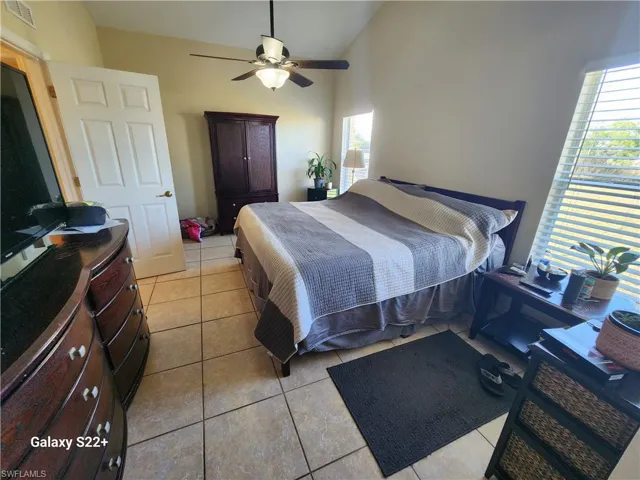 Bedroom with ceiling fan, lofted ceiling, and light tile patterned floors