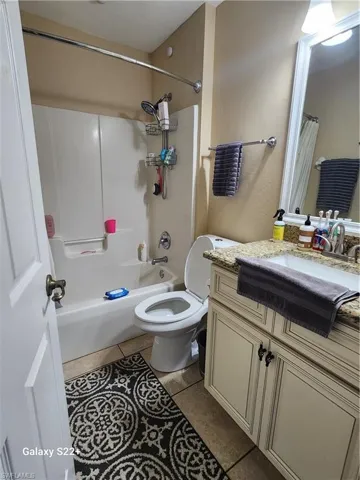 Full bathroom with tile patterned flooring, vanity, toilet, and shower / tub combo with curtain