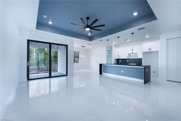Kitchen featuring decorative light fixtures, white cabinets, light tile flooring, and a raised ceiling