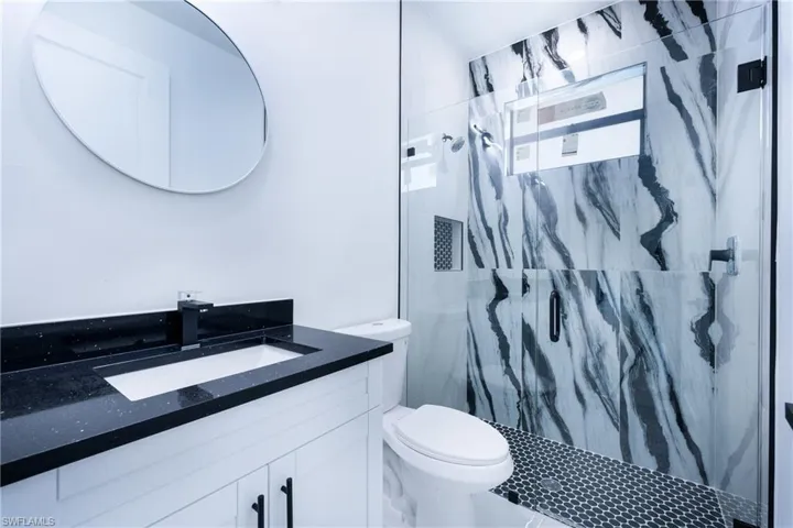 Bathroom featuring tiled shower, vanity, and toilet