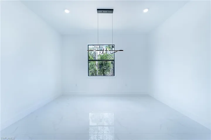 Tiled empty room featuring a chandelier