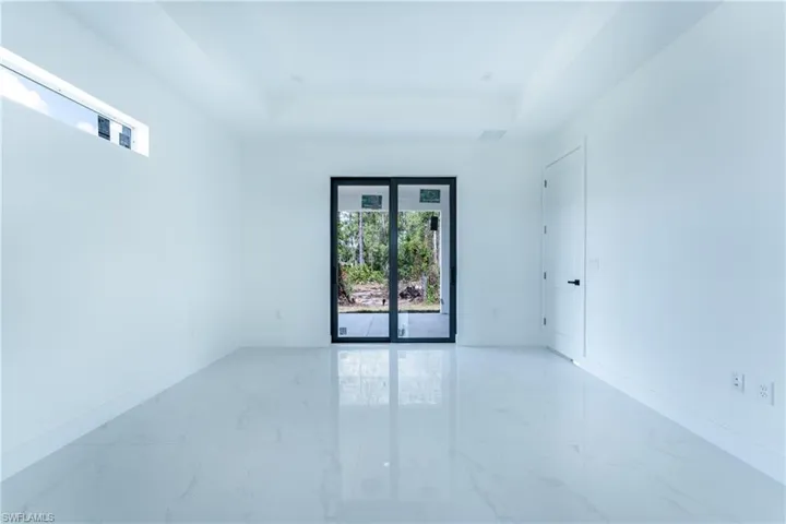 Unfurnished room with light tile flooring and a tray ceiling