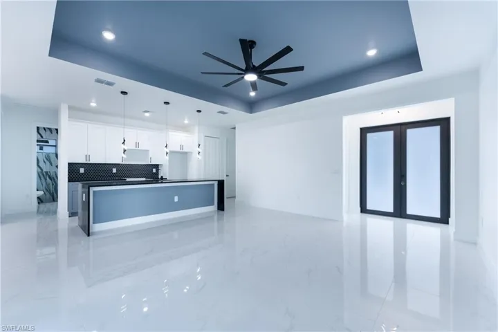 Kitchen with decorative light fixtures, backsplash, light tile flooring, and a raised ceiling
