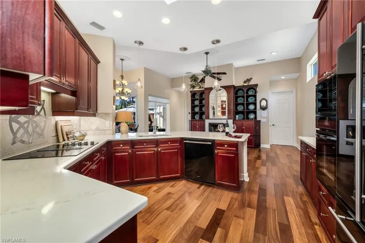 Kitchen with quartz countertops, cherry cabinetry, and beautiful engineered wood floors that flows hroughout most of the home.