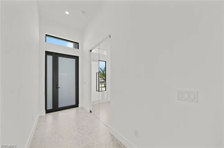 Entrance foyer with baseboards, a high ceiling, and recessed lighting