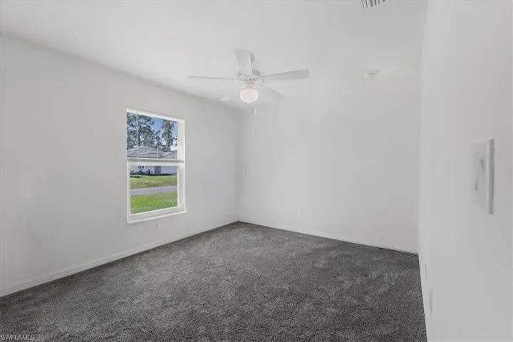 Spare room featuring dark colored carpet and ceiling fan