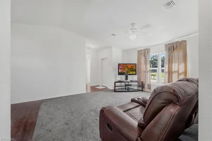 Living room with wood finished floors, vaulted ceiling, and ceiling fan