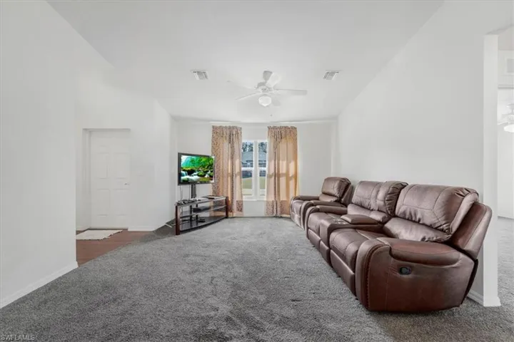 Living area featuring dark carpet and a ceiling fan