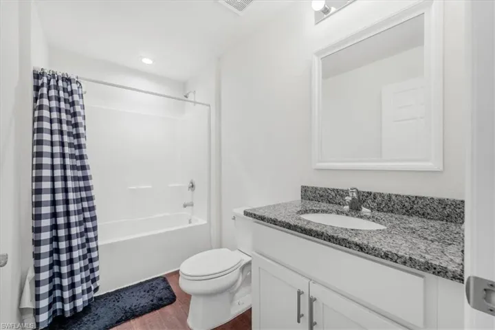 Full bath featuring shower / tub combo, vanity, dark wood-style flooring, and recessed lighting