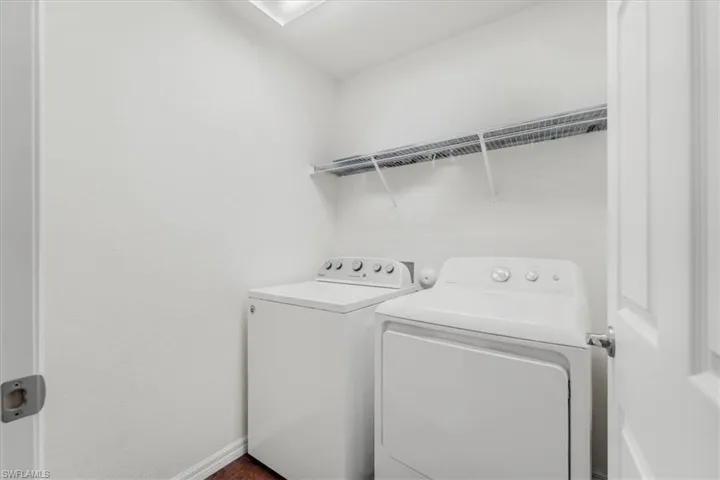 Washroom featuring washing machine and dryer and baseboards