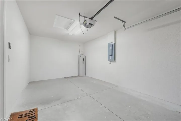 Garage featuring water heater, electric panel, and a garage door opener