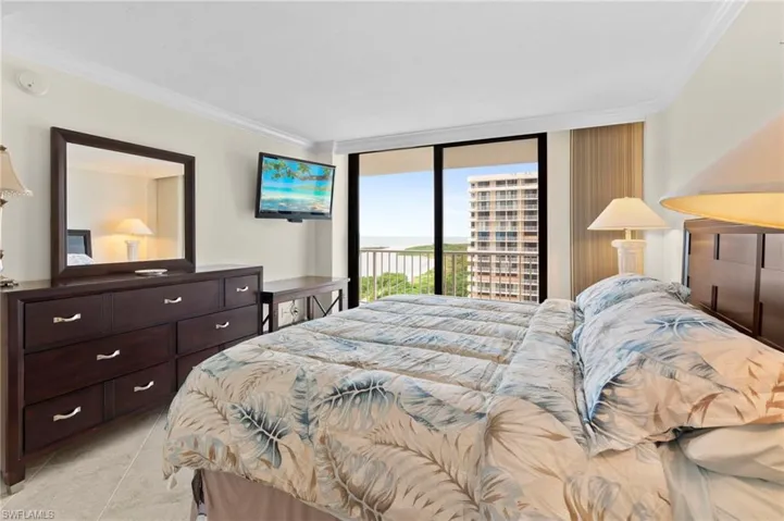 Bedroom with access to outside, light tile patterned floors, ornamental molding, and expansive windows