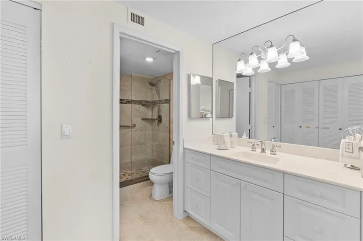 Bathroom with vanity, tile patterned floors, toilet, and tiled shower