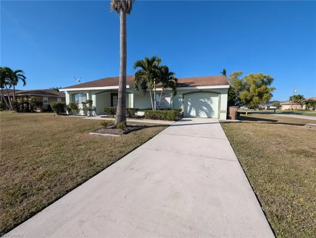 Ranch-style house featuring a front lawn, stucco siding, driveway, and an attached garage