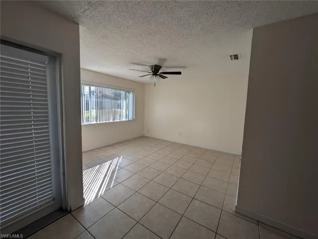 Unfurnished room with a textured ceiling, light tile patterned floors, and a ceiling fan