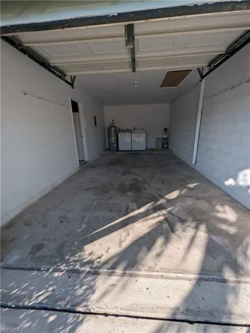 Garage with water heater, concrete block wall, and washer and dryer