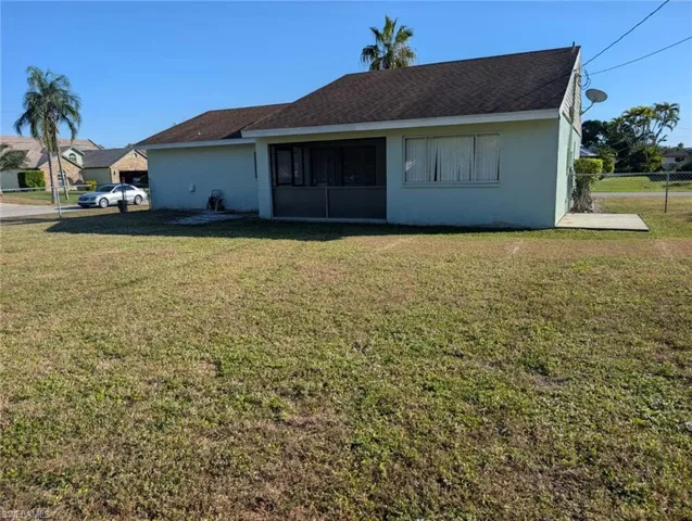 Rear view of property featuring stucco siding, a sunroom, and roof with shingles