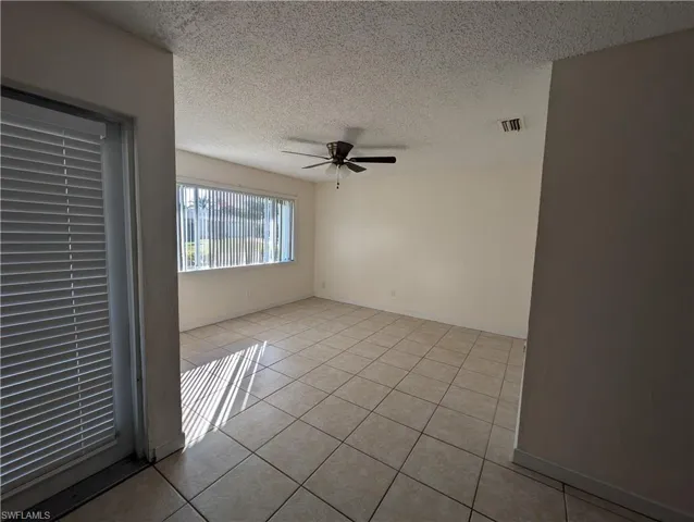 Spare room with a textured ceiling, light tile patterned flooring, and a ceiling fan