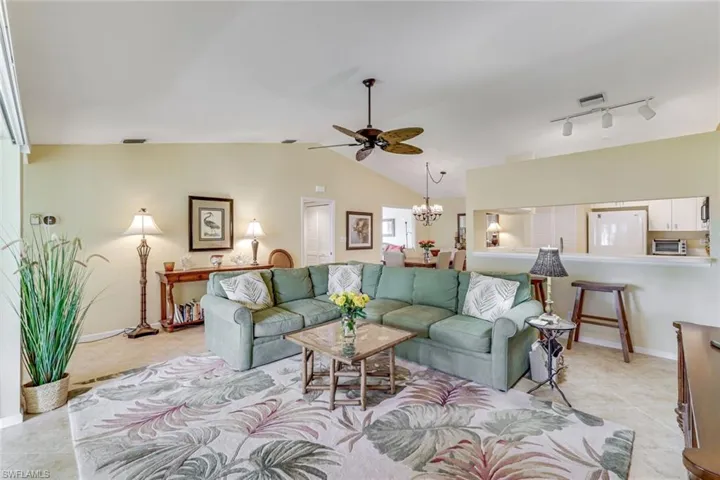 Vaulted ceilings highlight this living area featuring neutral-toned walls and tile flooring
