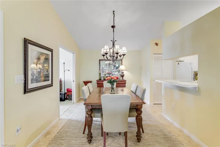 Dining area featuring a chandelier, tile flooring, and a pass-through window to the kitchen