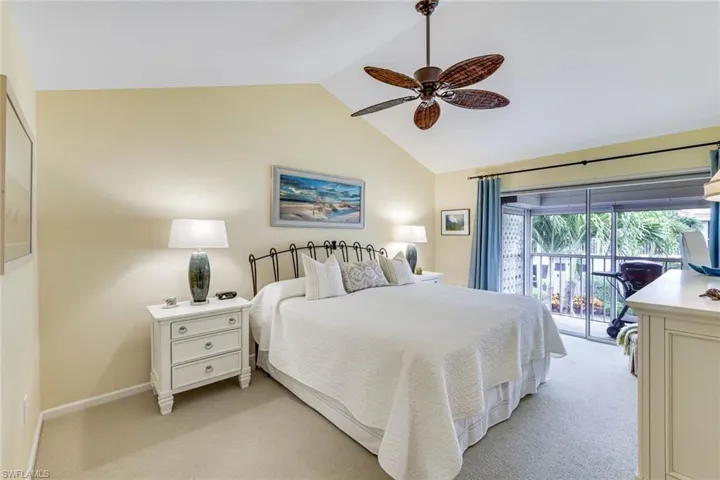 Vaulted ceiling bedroom featuring a ceiling fan, carpeted flooring, and direct access to an outdoor screened enclosure