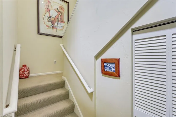 Carpeted staircase featuring white handrails and bi-fold louvered doors