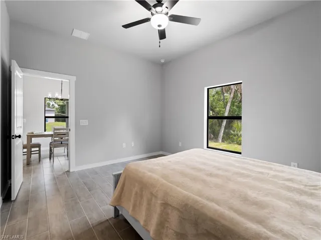 Bedroom with ceiling fan with notable chandelier and wood-type flooring