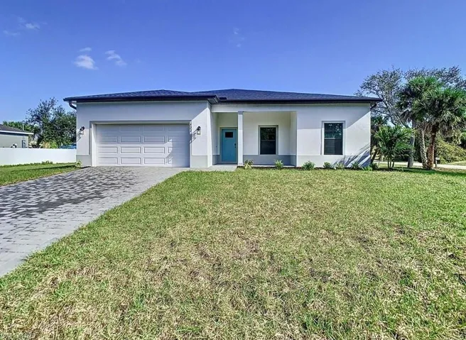 View of front facade featuring a garage and a front lawn