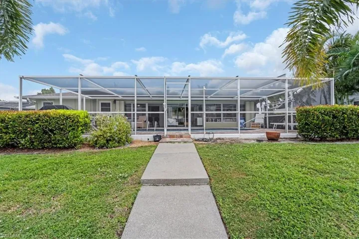 Rear view of house featuring glass enclosure, a sunroom, an outdoor pool, and a lawn