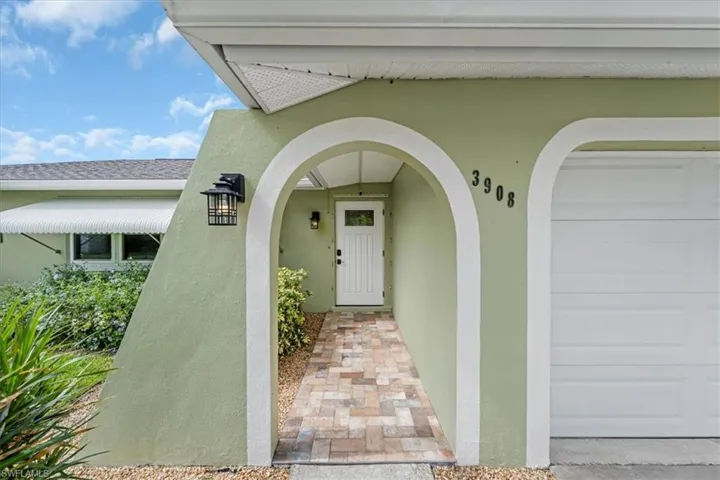 View of exterior entry featuring stucco siding, a garage, and a shingled roof