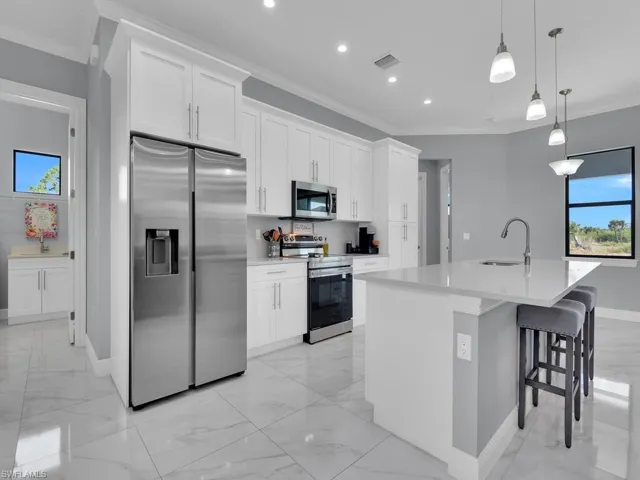 Kitchen with baseboards, appliances with stainless steel finishes, a sink, and a wealth of natural light