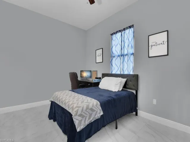 Bedroom featuring baseboards, marble finish floor, and ceiling fan