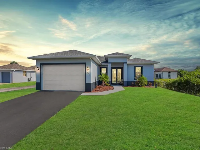 Prairie-style home featuring aphalt driveway, stucco siding, an attached garage, french doors, and a lawn