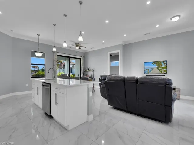 Kitchen with marble finish floor, baseboards, crown molding, and open floor plan