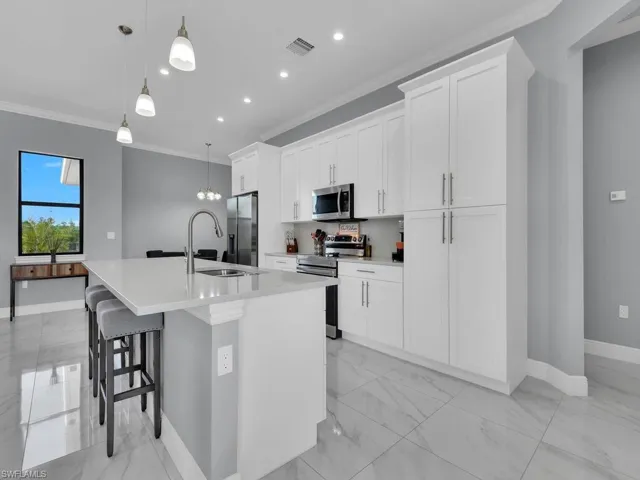 Kitchen with an island with sink, visible vents, a sink, crown molding, and appliances with stainless steel finishes