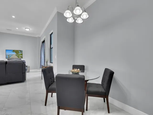 Dining room featuring marble finish floor, an inviting chandelier, ornamental molding, and baseboards