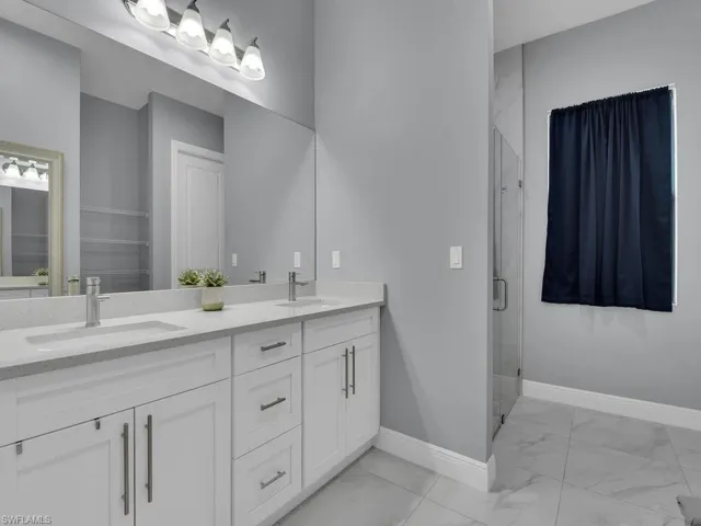 Full bath featuring baseboards, marble finish floor, a stall shower, and a sink