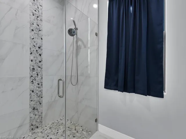 Full bath featuring baseboards and a shower stall