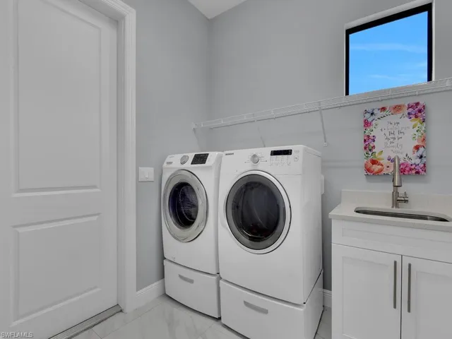Laundry area with a sink, marble finish floor, cabinet space, washing machine and dryer, and baseboards