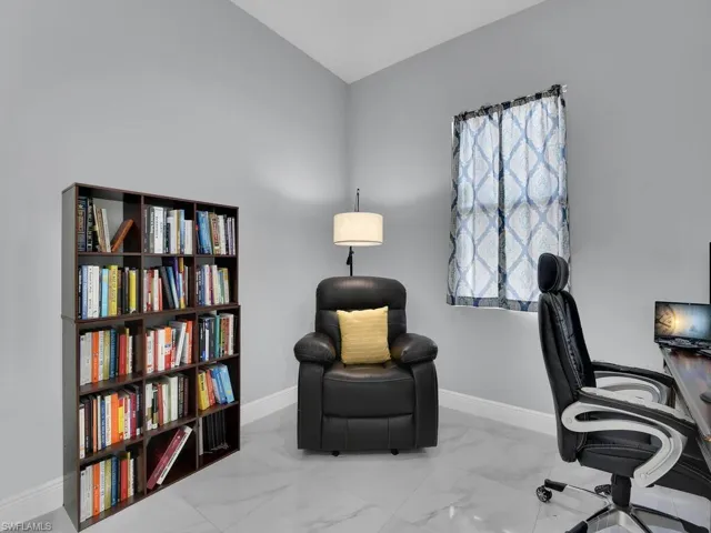 Office space with marble finish floor, baseboards, and vaulted ceiling