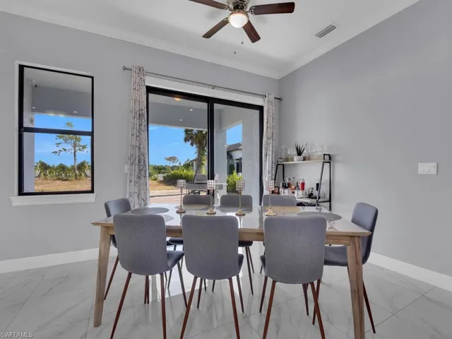 Dining room with marble finish floor, baseboards, crown molding, and visible vents