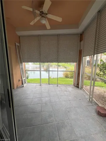 Unfurnished sunroom featuring healthy amount of natural light, ceiling fan, and a water view