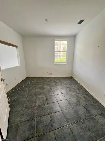 Unfurnished room with baseboards and dark tile patterned flooring