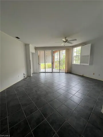 Empty room featuring dark tile patterned flooring, a ceiling fan, and crown molding
