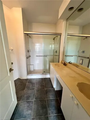 Bathroom featuring a stall shower, double vanity, and tile patterned floors